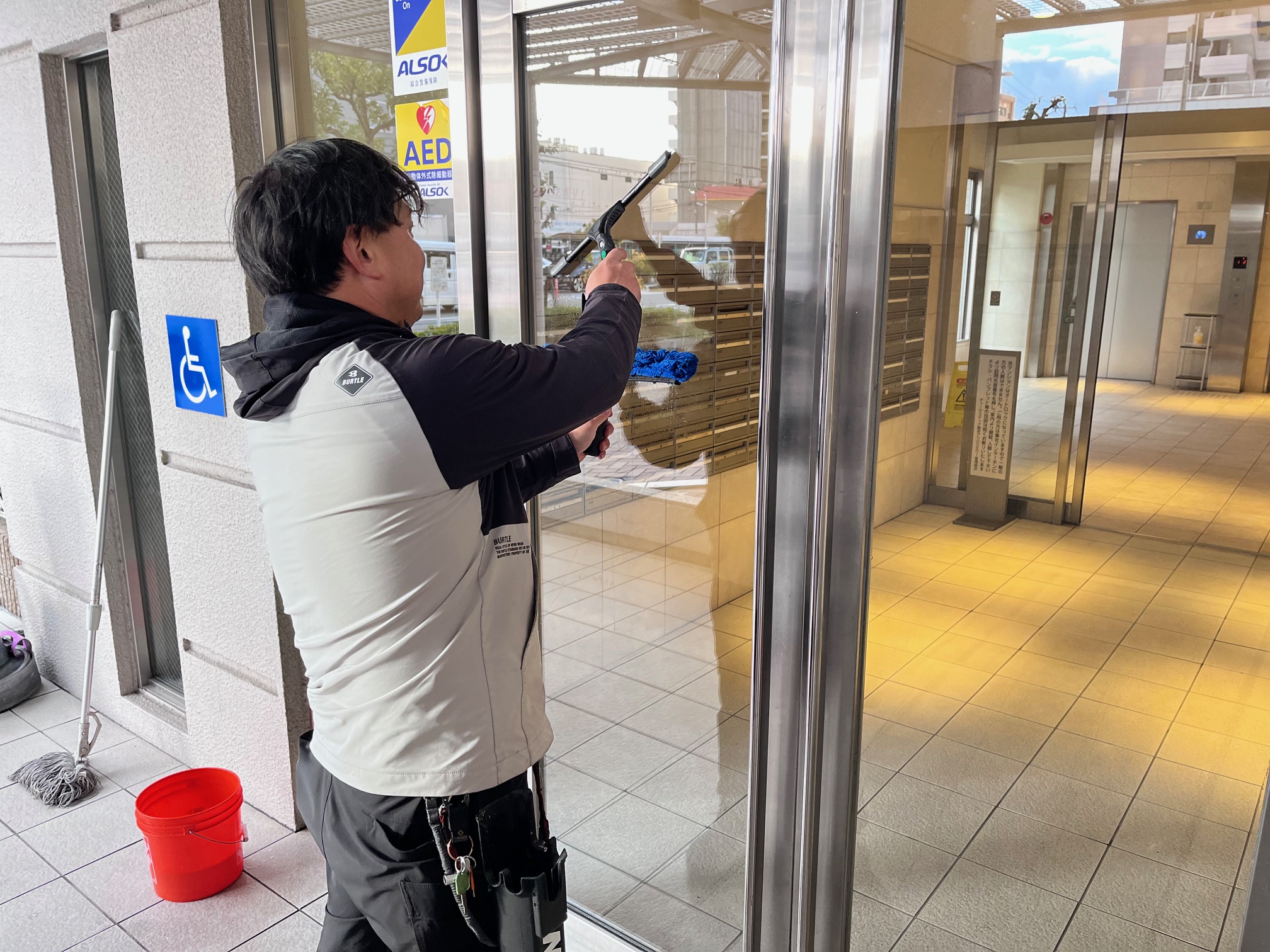 スクイージーを使って入口のガラスを清掃するスタッフ